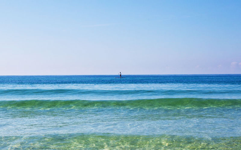 A paddle boarder near our Seacrest Beach vacation rentals