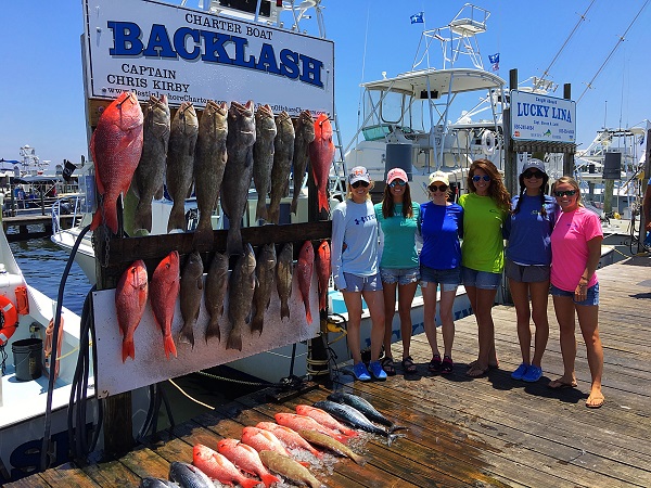 Girls in front of the Backlash Charter Boat sign and tons of fish