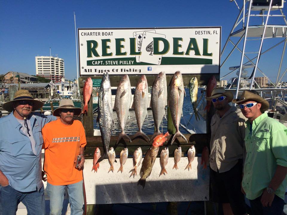 Guys with fish at the Reel Deal sign