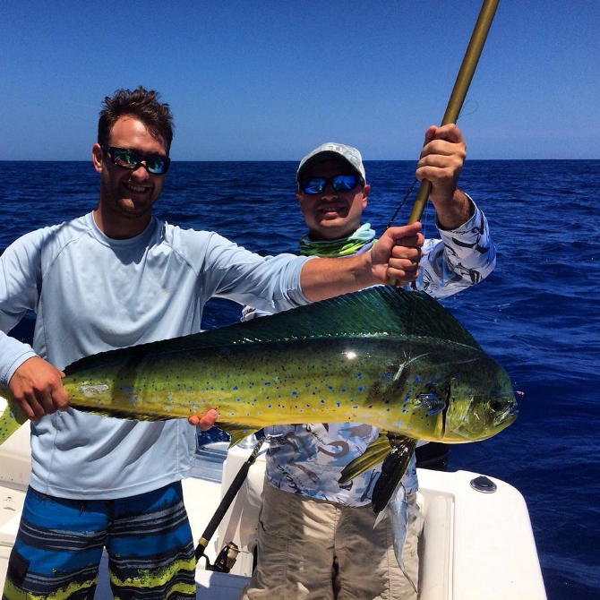 Two men with a dolphin fish on the Rolling Tide charter fishing boat