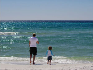 Dad and son on beach near their beach vacation rental on 30A